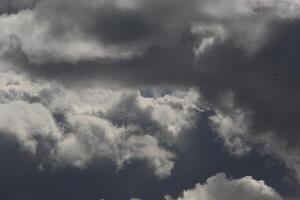 Cloudscape scenery, overcast weather above dark blue sky. Storm clouds floating in a rainy dull day with natural light. White and grey scenic environment background. Nature view. photo