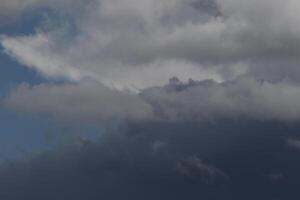 Cloudscape scenery, overcast weather above dark blue sky. Storm clouds floating in a rainy dull day with natural light. White and grey scenic environment background. Nature view. photo