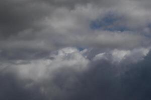 Cloudscape scenery, overcast weather above dark blue sky. Storm clouds floating in a rainy dull day with natural light. White and grey scenic environment background. Nature view. photo