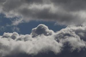 Cloudscape scenery, overcast weather above dark blue sky. Storm clouds floating in a rainy dull day with natural light. White and grey scenic environment background. Nature view. photo