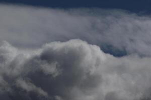 Cloudscape scenery, overcast weather above dark blue sky. Storm clouds floating in a rainy dull day with natural light. White and grey scenic environment background. Nature view. photo
