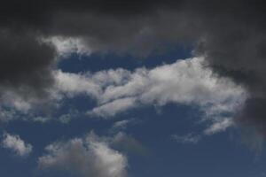 Cloudscape scenery, overcast weather above dark blue sky. Storm clouds floating in a rainy dull day with natural light. White and grey scenic environment background. Nature view. photo