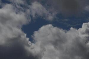 Cloudscape scenery, overcast weather above dark blue sky. Storm clouds floating in a rainy dull day with natural light. White and grey scenic environment background. Nature view. photo