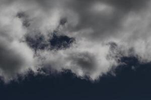 Cloudscape scenery, overcast weather above dark blue sky. Storm clouds floating in a rainy dull day with natural light. White and grey scenic environment background. Nature view. photo