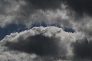 Cloudscape scenery, overcast weather above dark blue sky. Storm clouds floating in a rainy dull day with natural light. White and grey scenic environment background. Nature view. photo