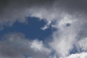 Cloudscape scenery, overcast weather above dark blue sky. Storm clouds floating in a rainy dull day with natural light. White and grey scenic environment background. Nature view. photo