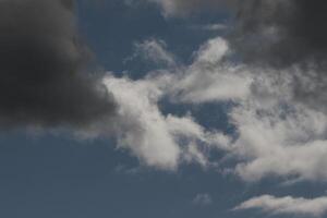 Cloudscape scenery, overcast weather above dark blue sky. Storm clouds floating in a rainy dull day with natural light. White and grey scenic environment background. Nature view. photo