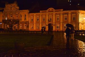 personas caminando en un lluvioso día en el calle. Unión cuadrado a noche, timisoara foto