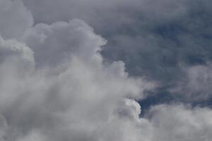 Cloudscape scenery, overcast weather above dark blue sky. Storm clouds floating in a rainy dull day with natural light. White and grey scenic environment background. Nature view. photo