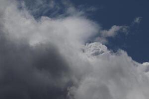 Cloudscape scenery, overcast weather above dark blue sky. Storm clouds floating in a rainy dull day with natural light. White and grey scenic environment background. Nature view. photo