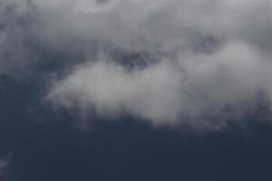 Cloudscape scenery, overcast weather above dark blue sky. Storm clouds floating in a rainy dull day with natural light. White and grey scenic environment background. Nature view. photo