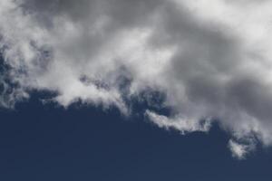 Cloudscape scenery, overcast weather above dark blue sky. Storm clouds floating in a rainy dull day with natural light. White and grey scenic environment background. Nature view. photo