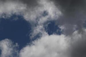 Cloudscape scenery, overcast weather above dark blue sky. Storm clouds floating in a rainy dull day with natural light. White and grey scenic environment background. Nature view. photo