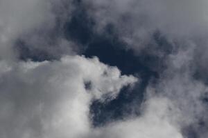 Cloudscape scenery, overcast weather above dark blue sky. Storm clouds floating in a rainy dull day with natural light. White and grey scenic environment background. Nature view. photo