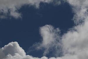 Cloudscape scenery, overcast weather above dark blue sky. Storm clouds floating in a rainy dull day with natural light. White and grey scenic environment background. Nature view. photo