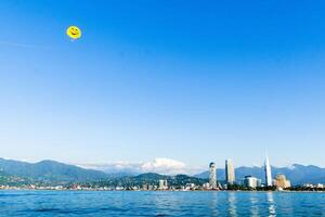 Batumi, Georgia -25th july, 2022 - Couple para-sailing with yellow smiley parachute on vacation on Batumi seaside resort on summer holiday vacation with city landmarks photo