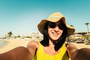 contento mujer turista sonrisa espectáculo pulgares arriba actitud para selfie a playa en vacaciones - medio años mujer o niña teniendo divertido sonriente a cámara - personas y Días festivos concepto foto