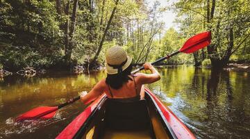 Back Rear View strong caucasian woman rowing Kayaking In Beautiful Lithuania countryside river - Zemeina. Action Camera POV Of Girl Paddling On canoe. Active holidays fun outdoors photo