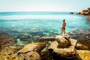 caucásico mujer turista disfrutar nadar en del Norte Chipre ayia napa bahía apuntalar con cristal claro azul Mediterráneo aguas y tranquilo rocoso caliza estructuras foto