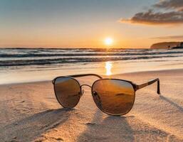 Sunglasses on sand on the beash, hot summer vacation time photo