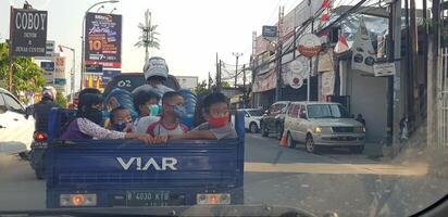 West Java in April 2019. A group of children ride a tricycle that has a vessel behind it. photo