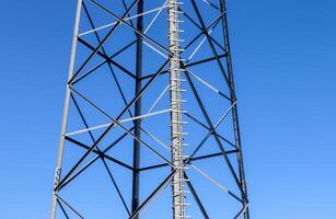 Antena eléctrica y torre transmisora de comunicaciones en un paisaje del norte de Europa contra un cielo azul foto