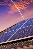 paneles solares que producen energía limpia en el techo de una casa residencial durante la puesta de sol. foto