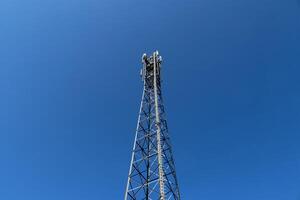 Antena eléctrica y torre transmisora de comunicaciones en un paisaje del norte de Europa contra un cielo azul foto