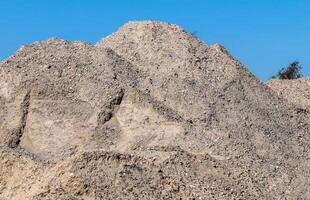 View into a gravel pit with piles of sand and some tire tracks photo