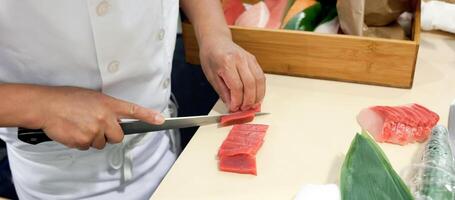 Hand was sliced fish to make sushi photo