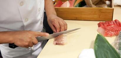 Hand was sliced fish to make sushi photo