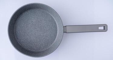 New granite frying pan on white background, top view. Empty fry pan with handle. photo