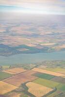 Land view through the airplane window. Fields, roads, rivers from a bird's eye view. Porthole. Look out the window of a flying plane. Top view of the ground photo