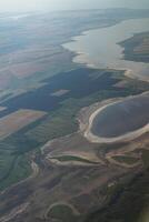 Land view through the airplane window. Fields, roads, rivers from a bird's eye view. Porthole. Look out the window of a flying plane. Top view of the ground photo