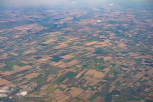 Land view through the airplane window. Fields, roads, rivers from a bird's eye view. Porthole. Look out the window of a flying plane. Top view of the ground photo