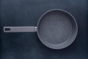 New granite frying pan on a gray background, top view. Empty fry pan with handle. photo