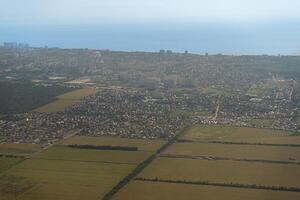 Land view through the airplane window. Fields, roads, rivers from a bird's eye view. Porthole. Look out the window of a flying plane. Top view of the ground photo