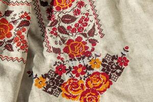 Ukrainian clothes embroidered shirt. Red orange and black threads background. Vyshyvanka is a symbol of Ukraine. Embroidery cross stitching. National Ukrainian stitch. Traditional clothing symbol photo