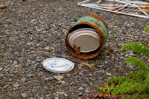 trash can is open and has a white lid on the ground photo