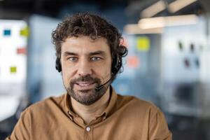 Professional male customer support representative wearing a headset, with a confident smile in a modern office setting. photo