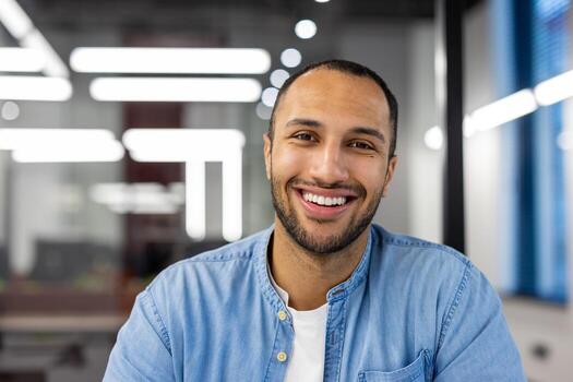 enfocado indio hombre a hogar en su vivo habitación, comprometido en un negocio llamar, mirando profesionalmente dentro el cámara en un casual ajuste. foto