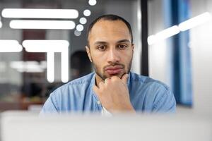 Focused professional man engaged in work at a contemporary office setting with modern lights and clean design. photo