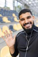 contento hombre ondulación a cámara en un Deportes estadio foto