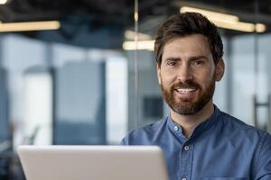 Focused professional man using laptop in a contemporary office space, exuding confidence and expertise. photo