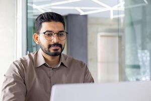 enfocado indio empresario utilizando un ordenador portátil a su oficina espacio de trabajo, encarnando profesionalismo y dedicación. foto