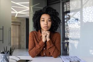 Young professional woman engaged in a call, looking directly at the camera with a thoughtful expression in a modern office setting. photo