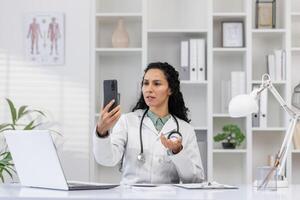 un trastornado hembra médico en un laboratorio Saco usos un teléfono inteligente en su oficina, expresando frustración o preocupación durante un conversación. foto