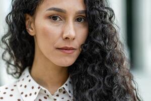 Close-up of an elegant curly-haired woman in a stylish polka-dot blouse. The image captures a fashionable female detail, perfect for beauty and fashion themes. photo