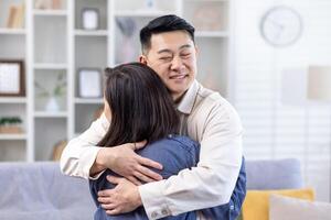 Happy asian couple man and woman together at home smiling and hugging, family in living room. photo
