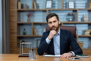 A poised mature businessman reflects deeply while sitting in a classic home office, exuding professionalism and confidence. photo